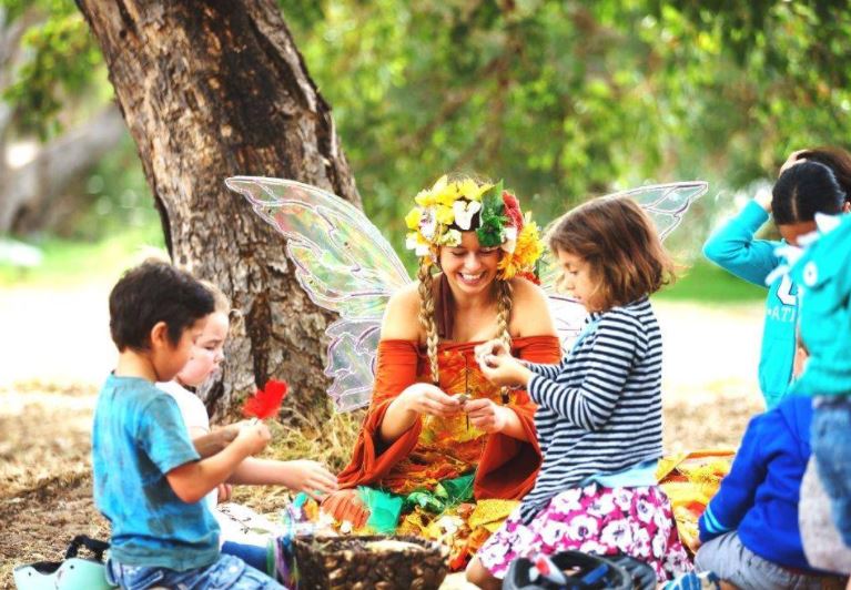 four chuldren making flower wreaths with fairy