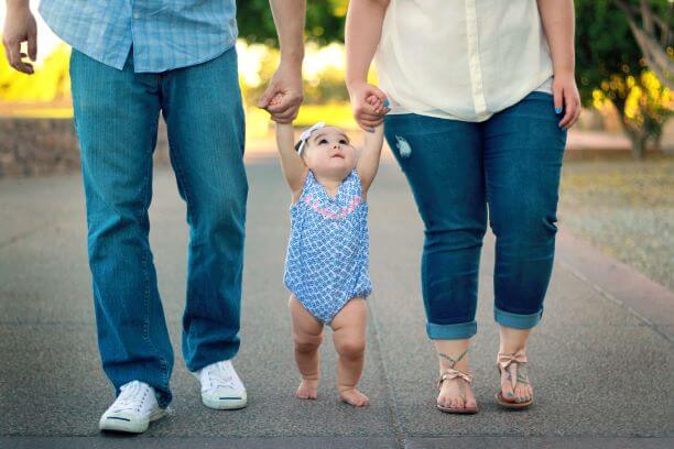 baby and parents holding hands