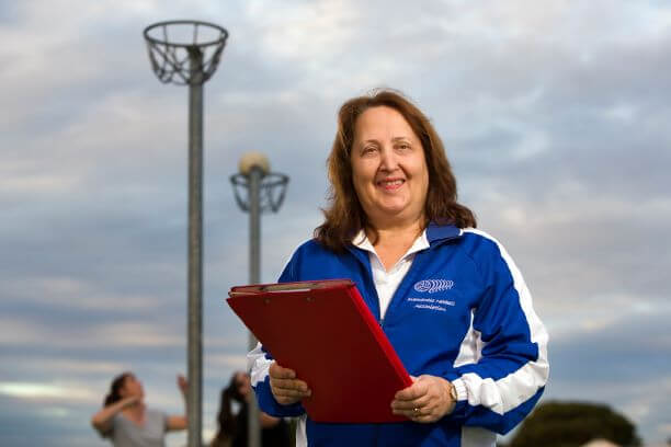 lasy with clipboard with netball hoops in background