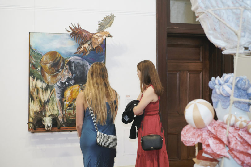 Two women looking at a painting during an exhibition