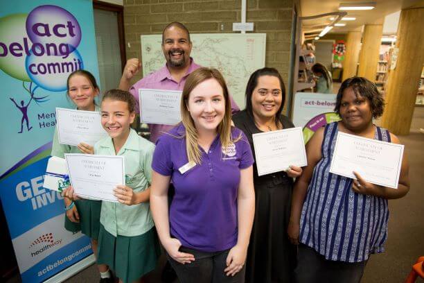 School students and adults holding certificates for an Act Belong Commit course