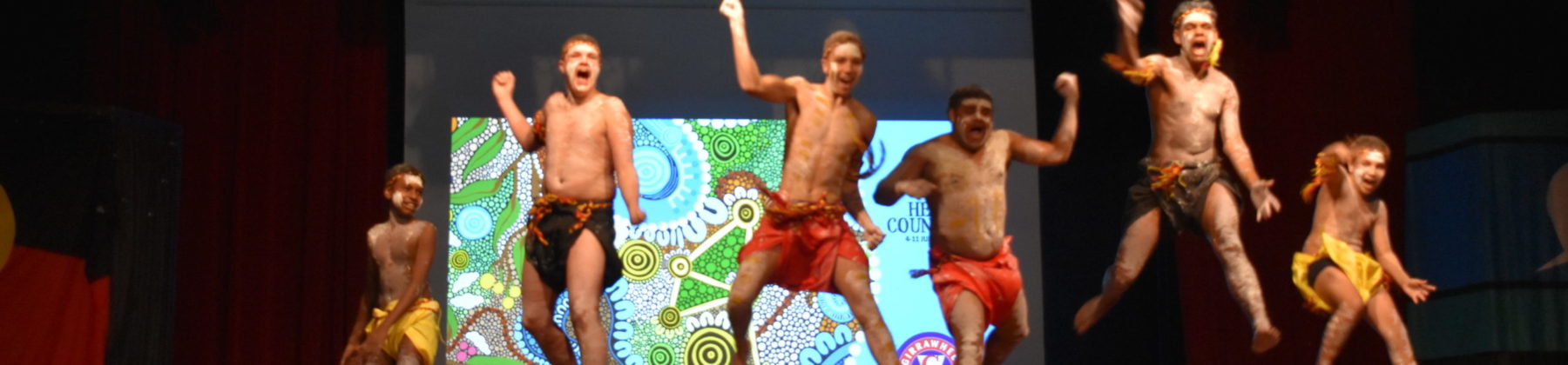 Aboriginal boys painted in traditional body jumping on stage